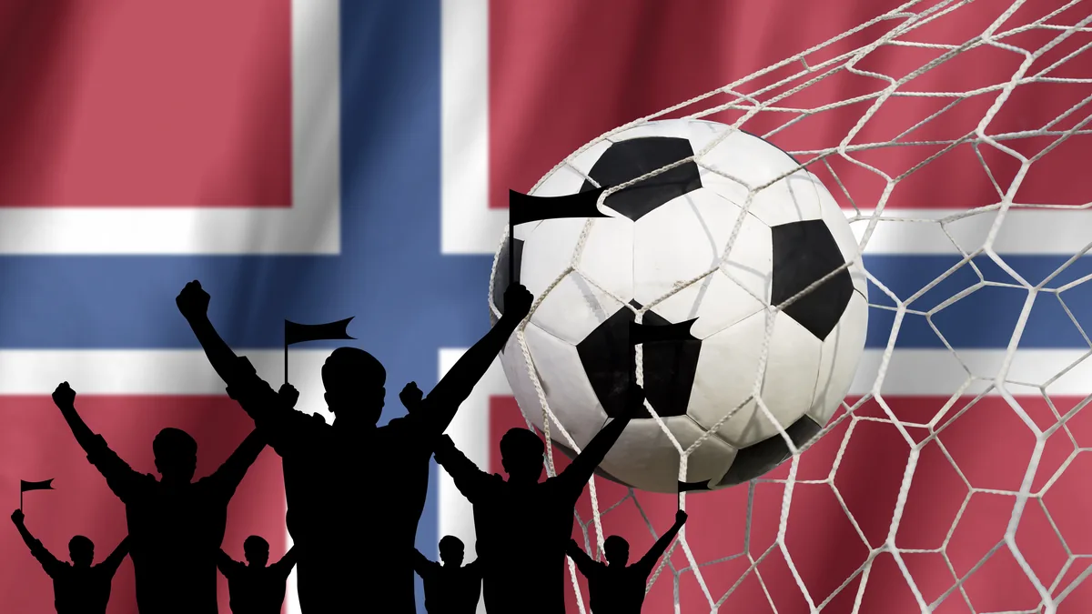 Fotball i nettmaskene og jublende supportersilhuetter mot et norsk flagg